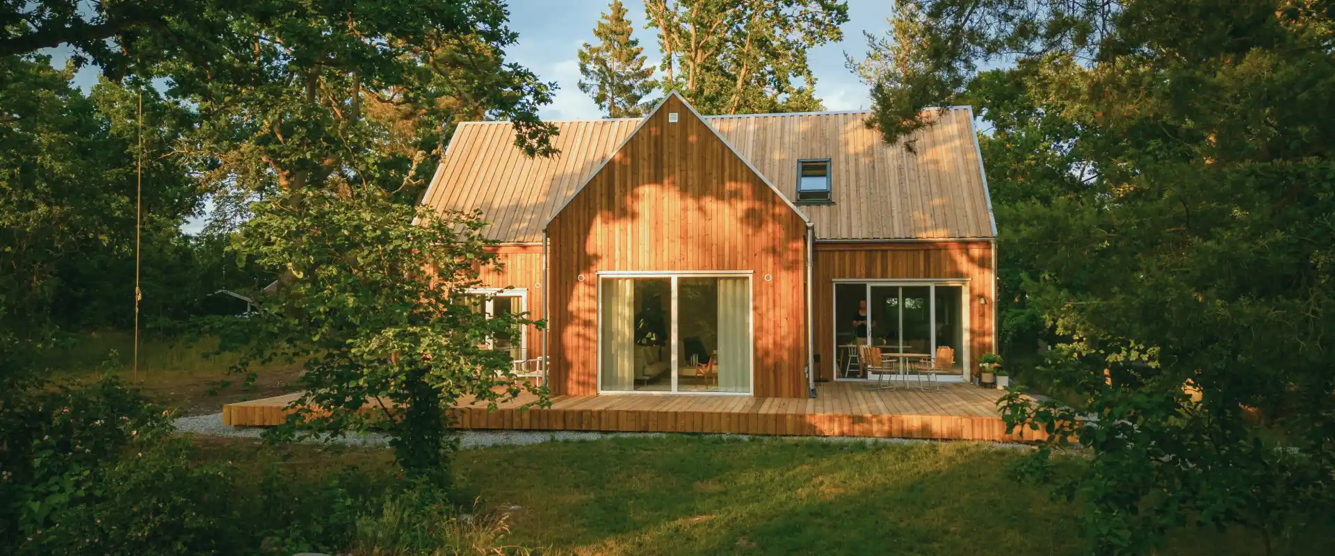 Une maison kit en bois de Trähus, construite en balieue. Elle possède de grandes baies vitrées pour laisser la lumière naturelle pénétrer dans le bâtiment.